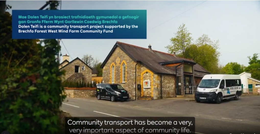tTill image of the Brechfa Windfarm video, showing Brechfa Village Hall, and dolen teifi bus and car.